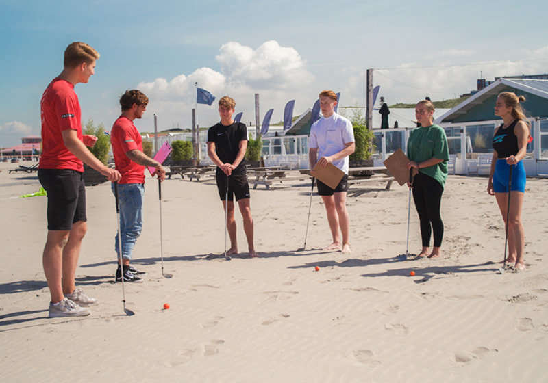 groep krijgt uitleg over beachgolf